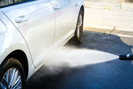 The side doors of a white Volkswagen car are cleaned with a high-pressure cleaner. © ThePhotoFab