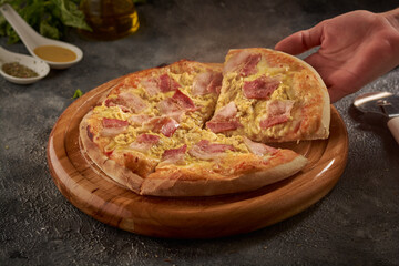 Hand grabbing a piece of delicious pizza on a wooden board