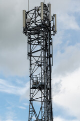 A cell phone tower or mobile phone mast with the remnants of a large birds nest on a landing platform approximately half way up