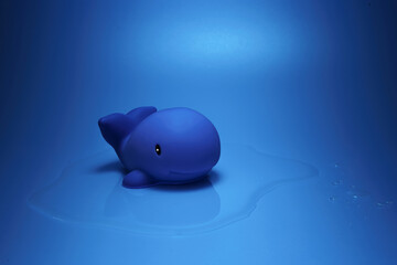 Creative composition of toy dolphin placed on blue surface for ocean concept in studio
