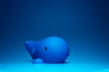 Creative composition of toy dolphin placed on blue surface for ocean concept in studio
