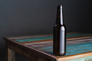 Dark glass bottle of alcoholic drink on painted square shaped wooden table at home