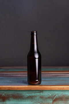 Dark glass bottle of alcoholic drink on painted square shaped wooden table at home