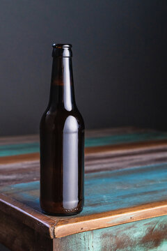 Dark glass bottle of alcoholic drink on painted square shaped wooden table at home