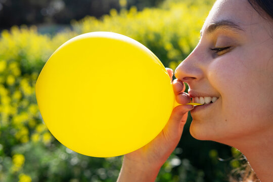 Crop female with bright balloon against blooming plants on sunny day
