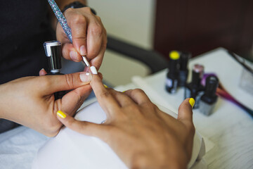 From above of crop unrecognizable manicurist doing nail art for female client in beauty salon in daylight