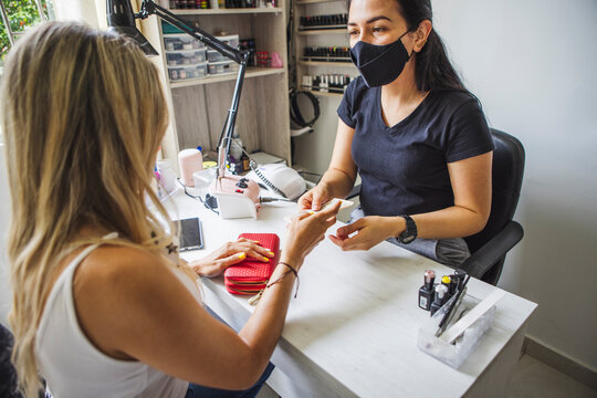 Side view of unrecognizable female customer paying to ethnic master after manicure in nail salon