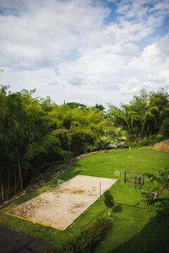 From above spacious sports ground with volleyball court and playground equipment located on lush grassy terrain in Colombia