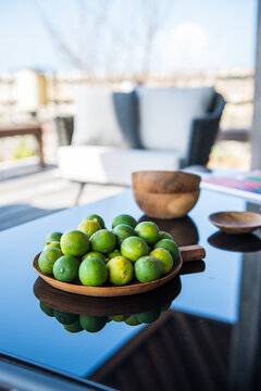 Exotic green mangoes on plate served on table with rip limes on sunny day in tropical resort