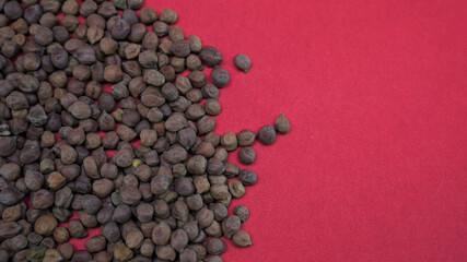 Top view of black chickpeas on the red surface - space for text