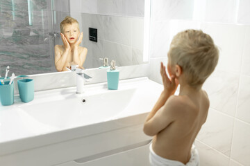 six-year-old boy applies aftershave like dad in the morning in the bath, hygiene in the morning