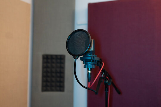 Pop filter and modern dynamic mic with wires in empty sound studio on blurred background