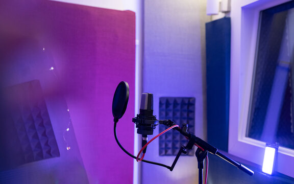 Pop filter and modern dynamic mic with wires in empty sound studio on blurred background