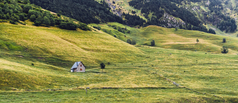 Scenic view of countryside constructions on hillside between majestic mountains in Aran Valley in Lleida Catalonia Spain in summer