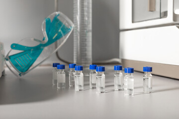 Similar small transparent bottles with liquids against protective glasses on table in cannabis lab
