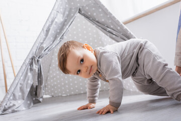 baby boy in romper crawling near tipi at home © LIGHTFIELD STUDIOS