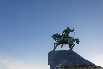 Monument to the horseman against the background of the blue sky. A beautiful stone monument. Evening sky. A colorful monument.