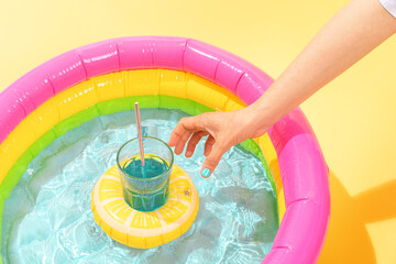 paddling pool with an inflatable in the shape of a lemon with a hand holding a cocktail