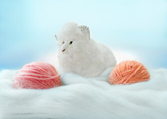 Two balls of wool yarn and a wool sheep on a background of white wool. The concept of creativity,...