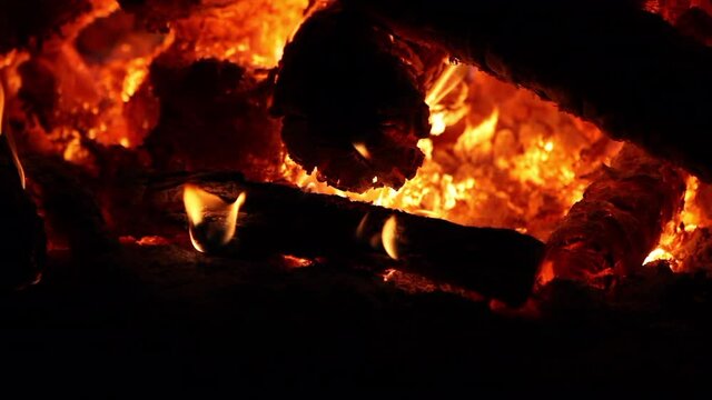 Pi&ntilde;a del bosque quem&aacute;ndose en una chimenea con llamas amarillas y rescoldos rojos.