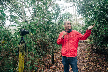 A man showing the natural environment where he is recording a video while speaking into a microphone