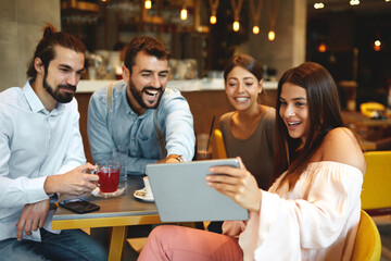 Group of Happy friends having with digital tablet in cafe