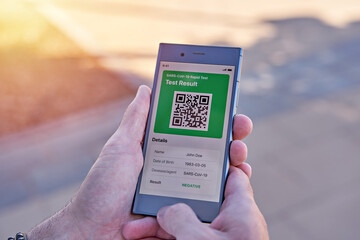 Man holding smartphone displaying on app mobile negative COVID-19 express test results. Immunity...