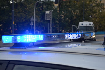 Niebieskie światła błyskowe policji. Napis policja na radiowozie polskiej policji. 