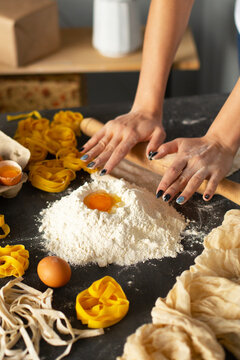 Closeup of process of making homemade pasta. Woman's hands roll out the dough