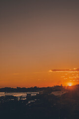 Photo of a sunset, taken from a high point where you can see the sea, the port, the buildings and...