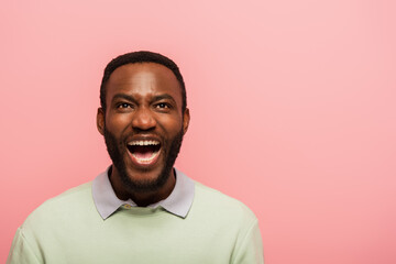 Cheerful african american man looking up isolated on pink