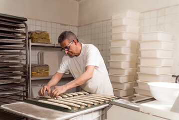 old authentic baker in bakery making organic bread and taking care of it with passion and care....