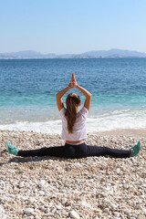 jeune fille pratiquant le yoga sur une plage - 434178125
