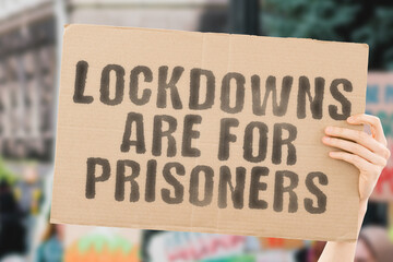 The phrase " Lockdowns are for prisoners " on a banner in hand with blurred background. Restrictions. Forbidden. Prohibition. Policy. Rules. Stressed. Depressive. Issue. Healthcare system