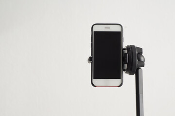 Smartphone mounted on a modern tripod in a vertical position. Space for text.