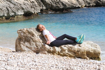 jeune fille se reposant sur un rocher sur une plage - 434180162