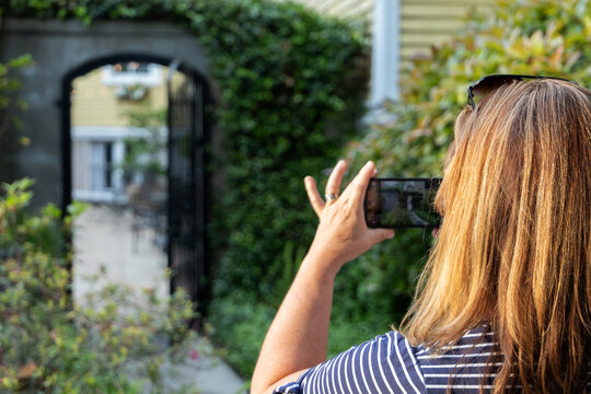 a female woman tourist in her 40's taking cell phone pictures of architecture in Savannah, Georgia in the spring