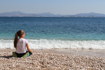 jeune fille meditant sur une plage - 434180732