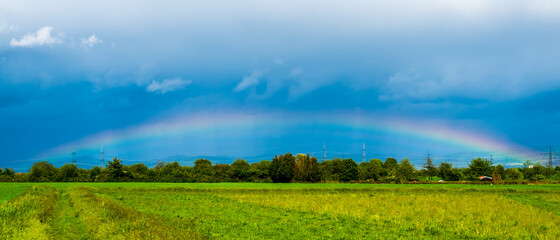 Rainbow in dark blue sky over landscape