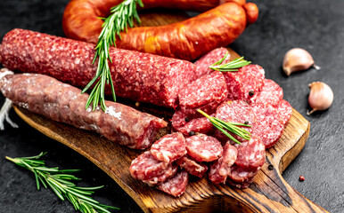 Assortment of smoked sausages and sausages with mold on a stone background	