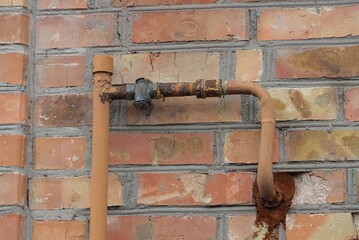 Fototapeta na wymiar iron gas pipe on brown brick wall outside
