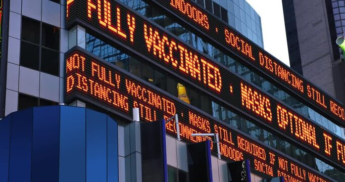 A Times Square stock market ticker informs pedestrians that masks are not required if fully vaccinated. Masks and social distancing were common practices to slow down the spread of COVID-19 during the