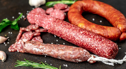 Assortment of smoked sausages and sausages with mold on a stone background	