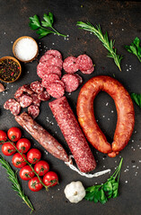 Assortment of smoked sausages and sausages with mold on a stone background	