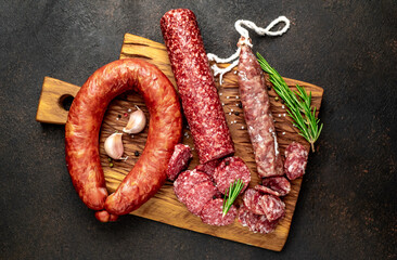 Assortment of smoked sausages and sausages with mold on a stone background	