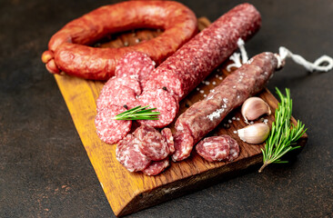 Assortment of smoked sausages and sausages with mold on a stone background	