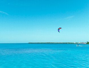 Man practicing kitesurfing on a bright sunny day. Background landscape of turquoise water and sky of the caribbean sea on Caye Caulker, Belize