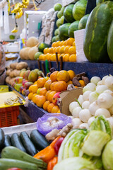 Colorful fruit and vegetables stand with watermelons, oranges, onions, and more