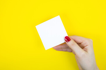 Blank white To Do List Sticker in woman hand. Close up of reminder note paper on the yellow background. Copy space. Minimalism, original and creative photo.