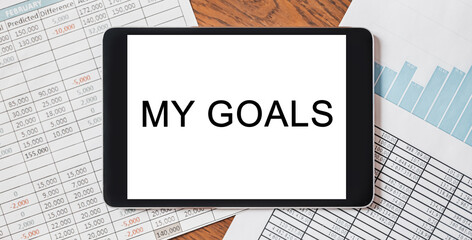 Tablet with text My goals on your desktop with documents, reports and graphs. Business and finance concept